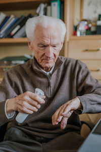 Senior man using hand sanitizer at home