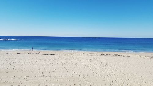 Scenic view of beach against clear blue sky