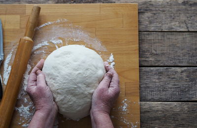 Cropped hands of woman kneading dough on table