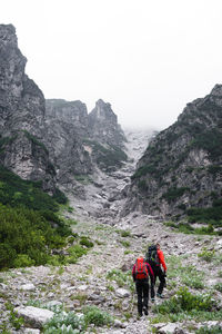 Rear view of people walking on mountain against clear sky