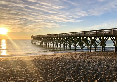 Pier over sea against sky during sunset