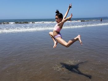 Full length of girl jumping at beach