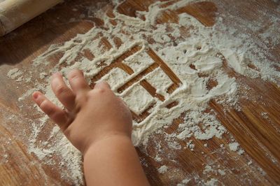 Cropped hands of girl playing with flour on table