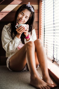 Portrait of woman drinking coffee while sitting at home