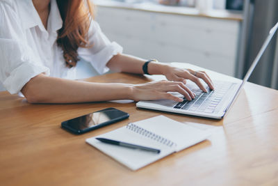 Midsection of woman using laptop on table