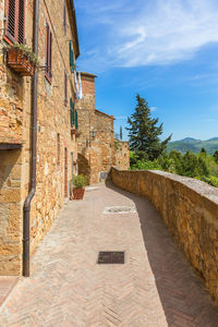 Footpath amidst buildings against sky