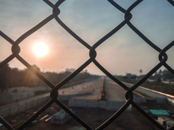 Full frame shot of chainlink fence against sky during sunset