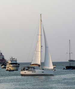 Sailboats sailing in sea against sky