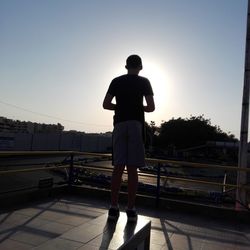 Full length of man standing on railing against sky