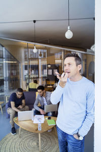 Businessman talking on mobile phone while colleagues discussing in background