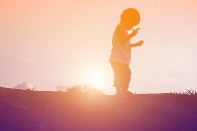 Man standing on field against sky during sunset