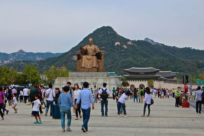 Crowd visiting statue of king sejong by gyeongbokgung against sky