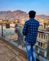 Rear view of man looking at city against sky