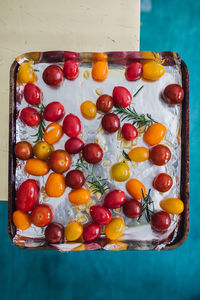 Raw whole cherry tomatoes with garlic and rosemary on foil-lined baking tray before roasting