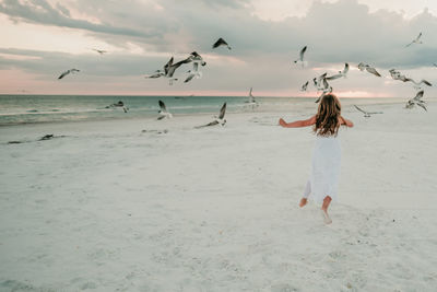 Rear view of woman on beach against sky