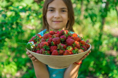 Portrait of cute girl holding strawberries in container