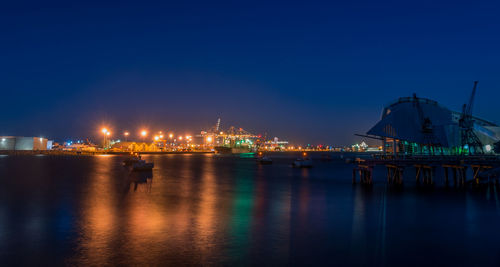 Illuminated commercial dock against clear blue sky at night