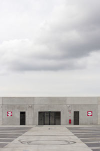 Empty road by building against sky