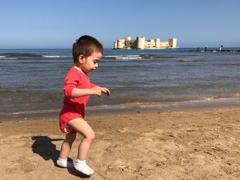 Boy on beach by sea against sky