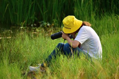 Back view of photographer  on grass field taking photo