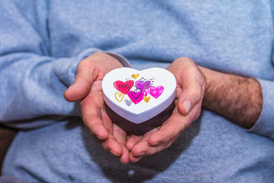 Midsection of man holding heart shape