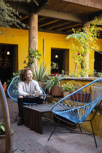 Man sitting on chair by table against building