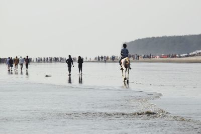 People on beach against clear sky