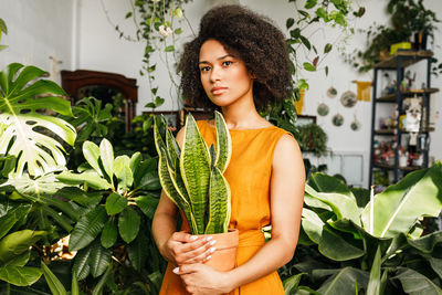 Portrait of girl holding while standing against plants