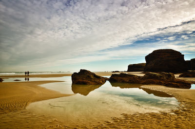 Rocks on beach against sky during sunset