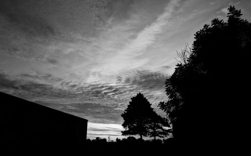 Low angle view of silhouette trees against cloudy sky