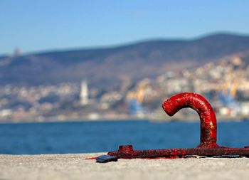 Red mooring hook on pier by mountain against sky