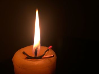 Close-up of lit candle in darkroom