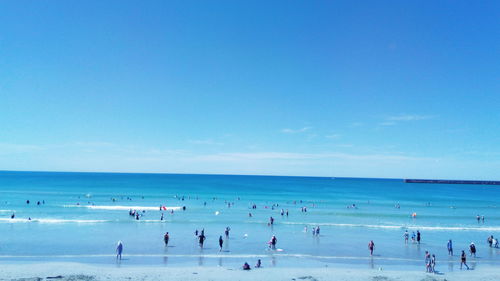 People at beach against blue sky