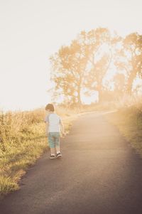 Rear view of boy walking on road