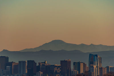 Silhouette buildings in city against clear sky during sunset