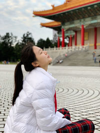 Side view of woman sitting on footpath