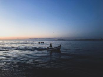 Silhouette boat in sea against clear sky during sunset