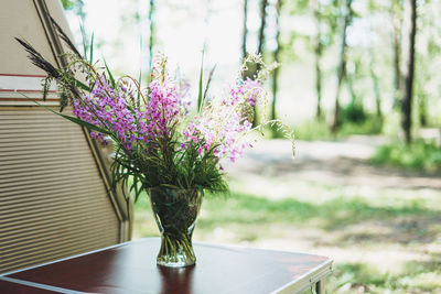 A bouquet of forest flowers in a vase on the table near the camper in forest