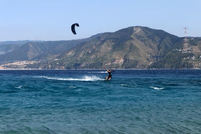 Man surfing in sea against clear sky