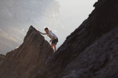 Rear view of woman on rock formations against sky