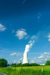 Smoke emitting from cooling tower on field against sky