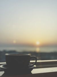 Close-up of coffee on table against sky during sunset