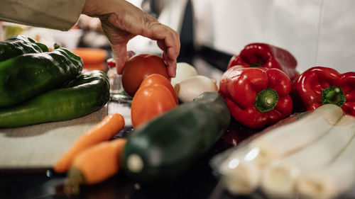 A female chef holding and picking a fresh tomato from vegetables on the table