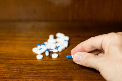 Simple pile of white, blue and yellow pills, medicines, pills stacked on brown background. 