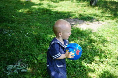 Side view of baby boy playing with ball at back yard