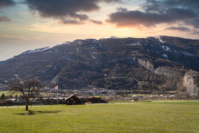 Scenic view of field by buildings against sky