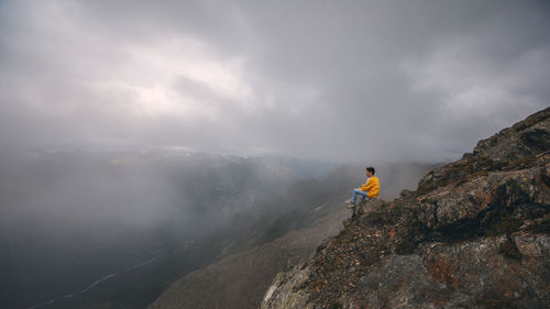 Rear view of man walking on mountain against sky