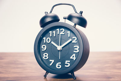 Close-up of clock on table against wall