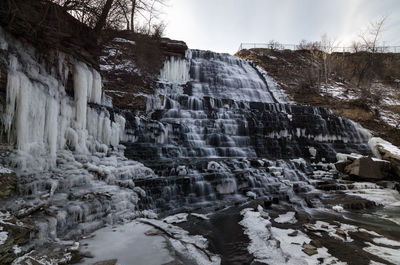 Scenic view of waterfall against sky during winter