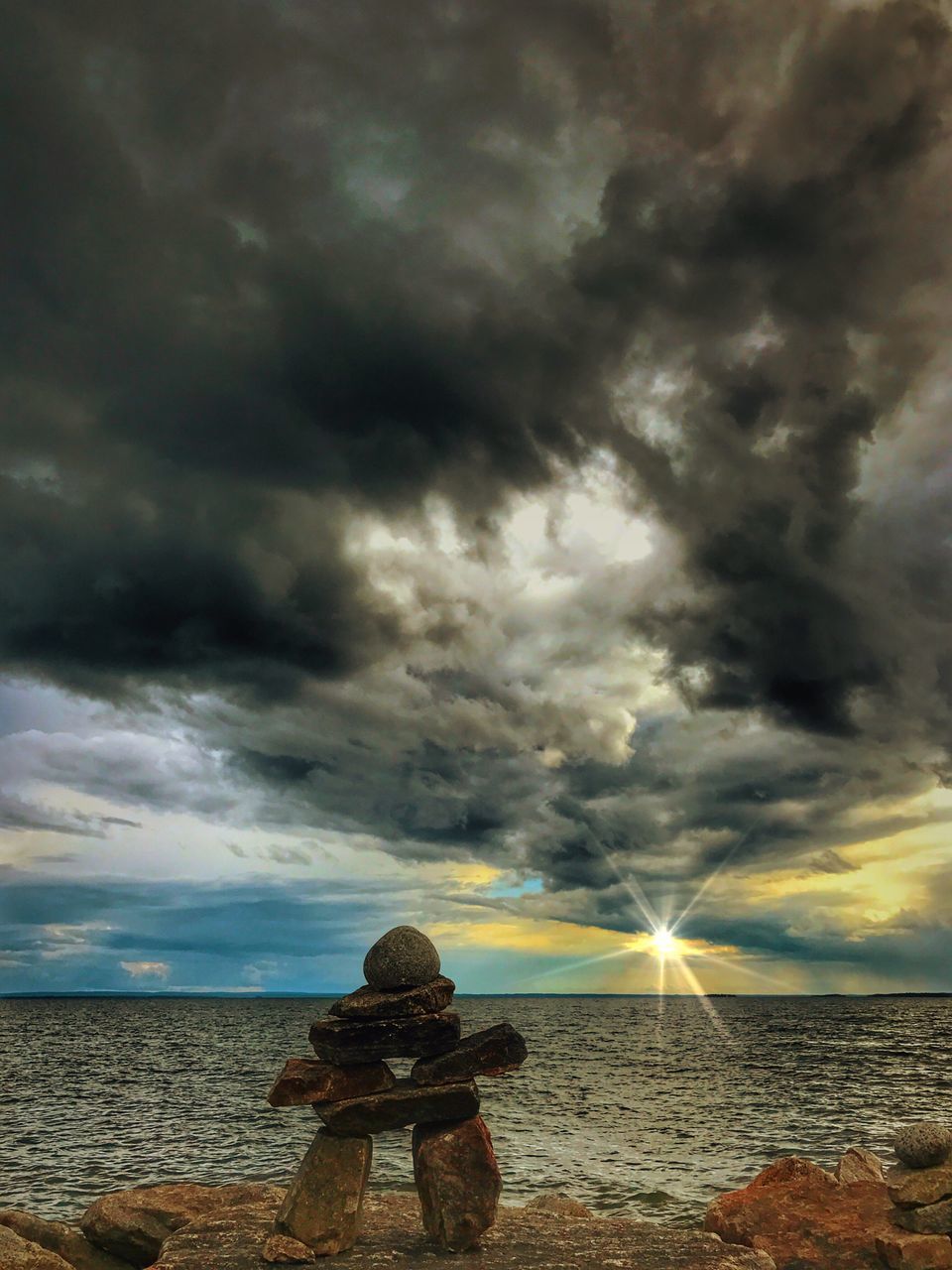 SILHOUETTE MAN AND WOMAN STANDING ON BEACH AGAINST STORM CLOUDS